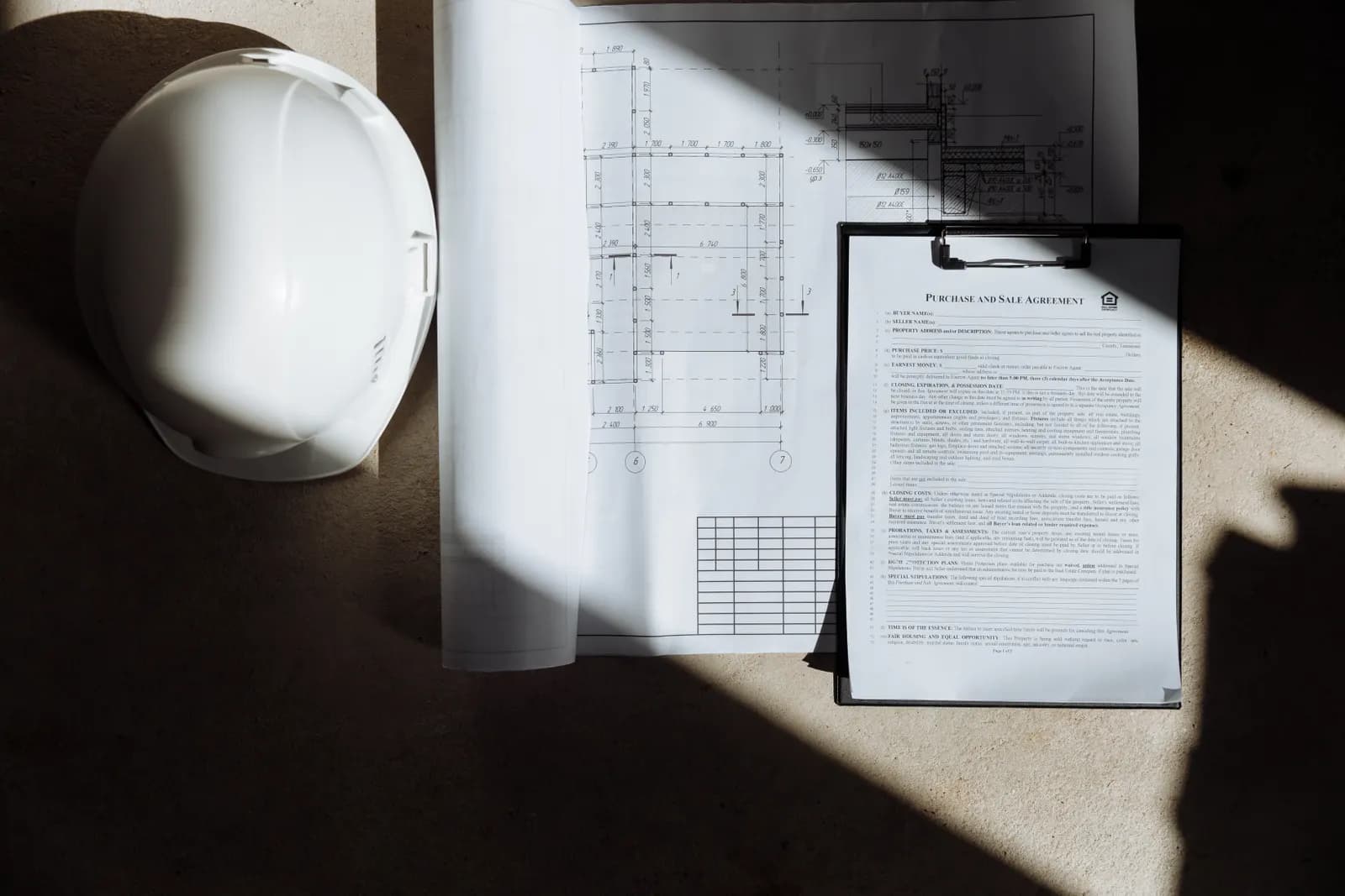 Bouwplannen, documenten en een veiligheidshelm op een werktafel